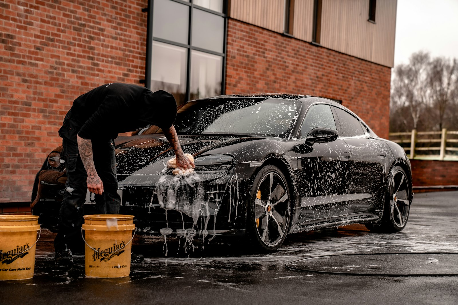 A premium car being hand washed with foam during a valet